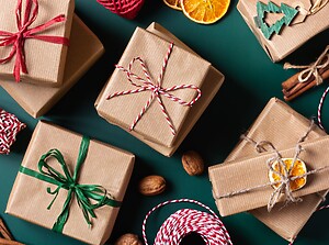 Weihnachtsgeschenke in Packpapier auf dunkelgrünem Hintergrund mit Orangenscheiben und Zimtstangen