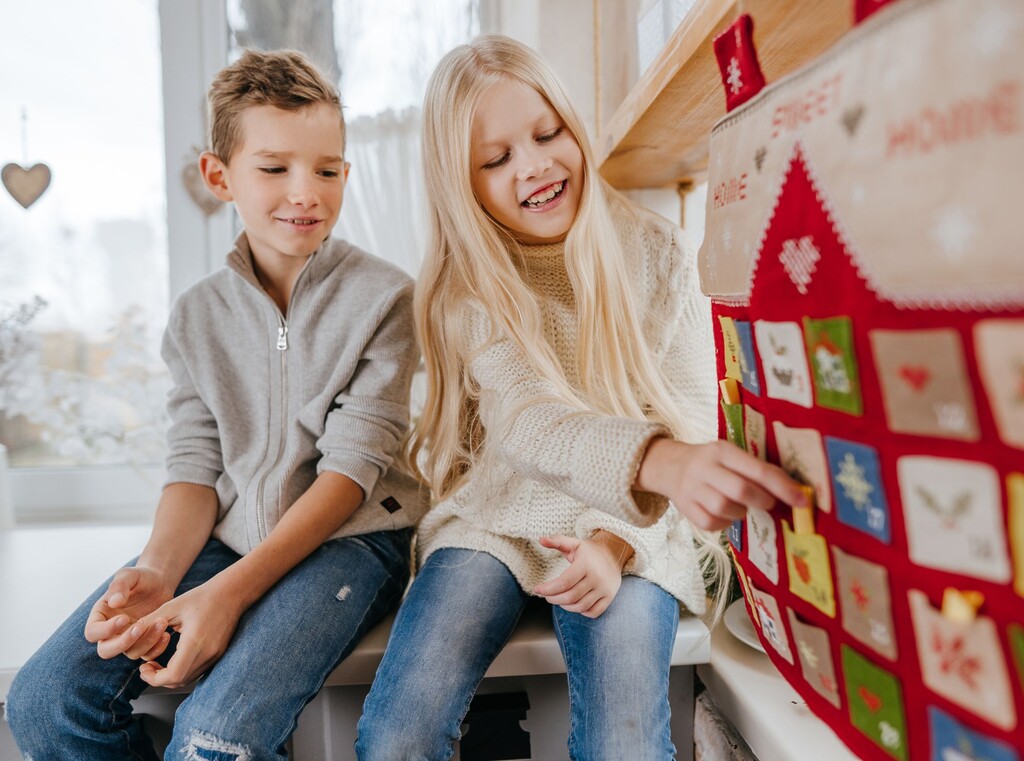 Zwei Kinder sitzen zusammen und öffnen einen Adventskalender