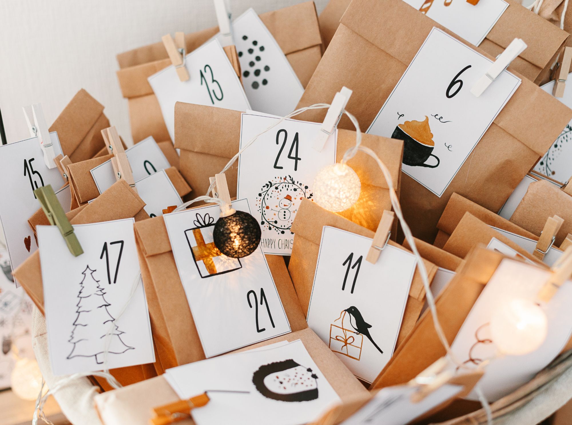 Ein selbstgemachter adventskalender mit papiertüten, nummerierten anhängern und einer lichterkette