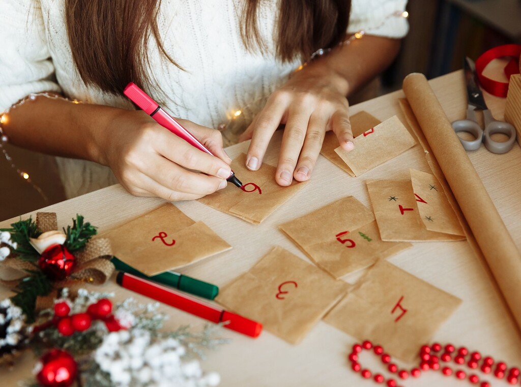 Zwei hände von oben, die einen adventskalender mit roten zahlen beschriften