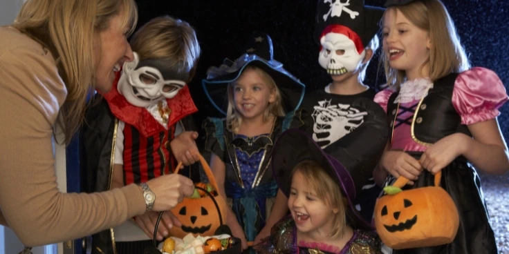 Halloween mit kindern – kreative kostüme, bastelideen und kinderfreundliche snacks 4 Kinder in halloween-kostümen bekommen süßigkeiten an der tür