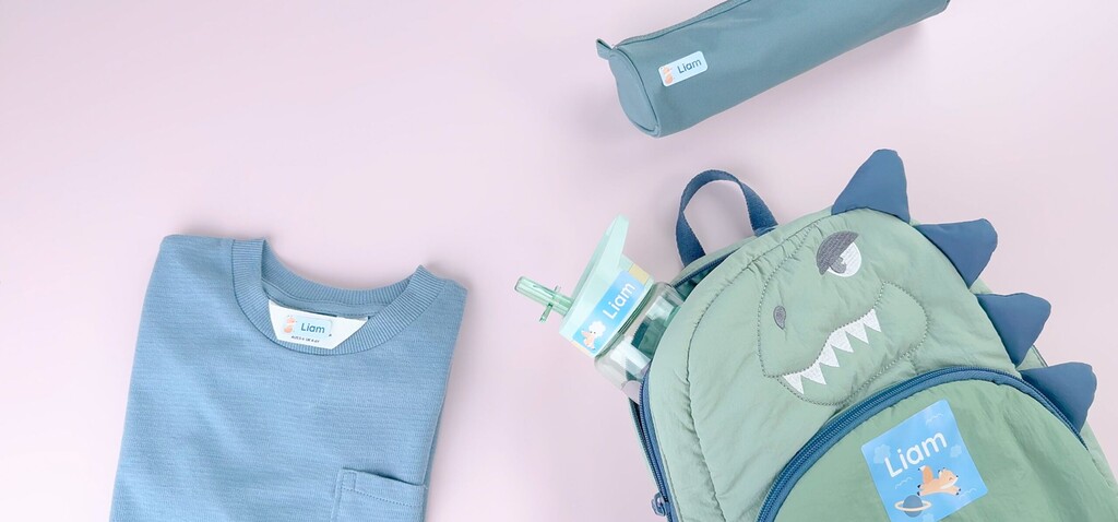 Personalisierte Namensaufkleber auf einem T-Shirt, einem Rucksack, einer Trinkflasche und einem Mäppchen