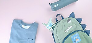 Personalisierte Namensaufkleber auf einem T-Shirt, einem Rucksack, einer Trinkflasche und einem Mäppchen