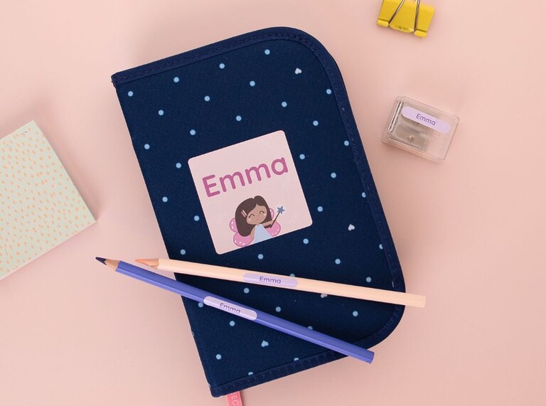 Blaues Federmäppchen mit einem personalisierten Namensaufkleber mit dem Text "Emma" sowie weiteren Schul-Utensilien, die ebenfalls mit Aufklebern personalisiert sind.