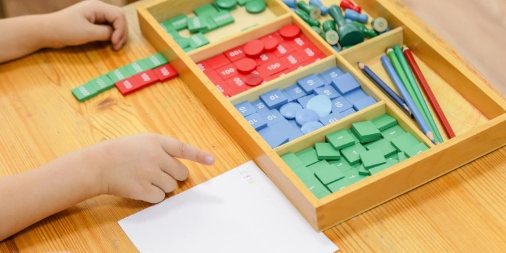 Montessori für vorschulkinder: so lernen sie mathe und sprache mit spaß 3 Kind arbeitet mit montessori-mathematikmaterialien auf einem holztisch.