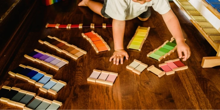 Kind sortiert montessori-farbtafeln auf dem boden im kinderzimmer