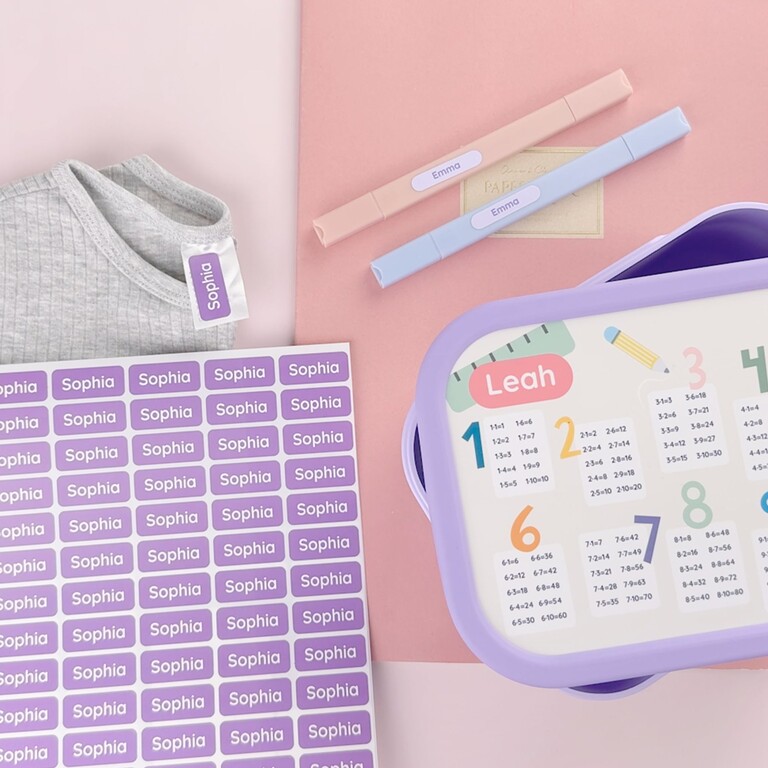 Namensaufkleber in verschiedenen Größen neben einer personalisierten Brotdose