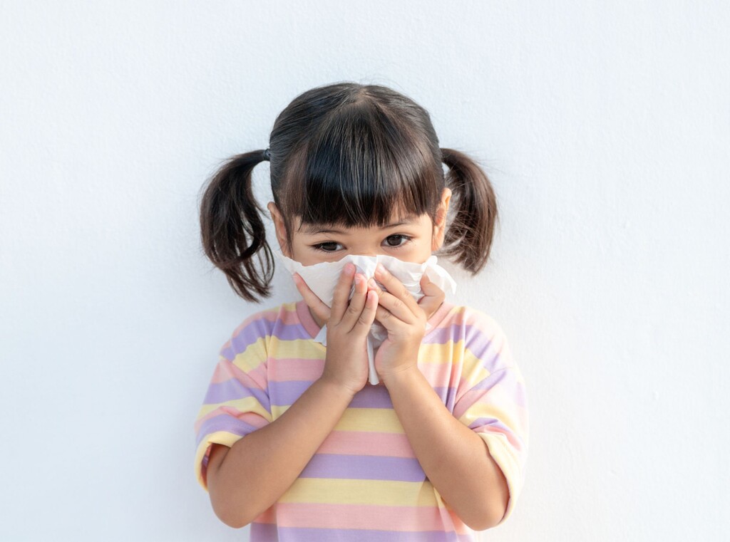 Kind schnäuzt sich mit einem Taschentuch in der Erkältungszeit