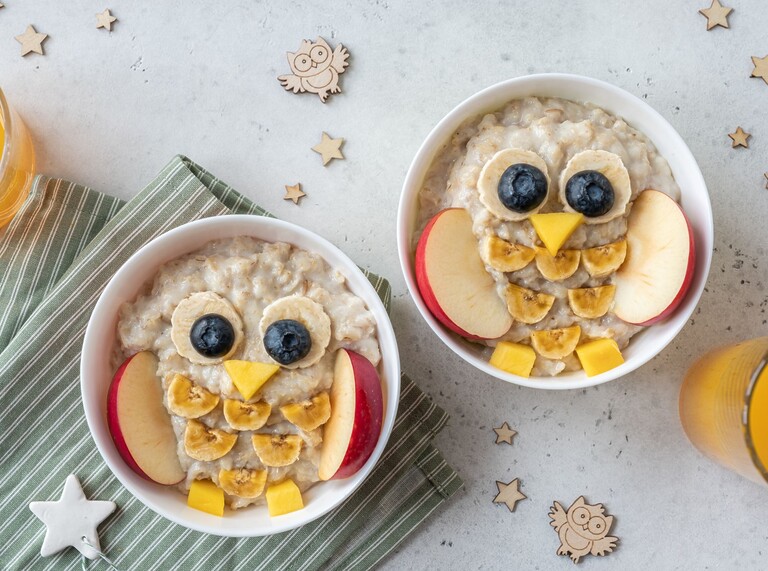 Zwei Schüsseln Haferbrei dekoriert als Eulen mit Früchten, gesundes Frühstück für Kinder
