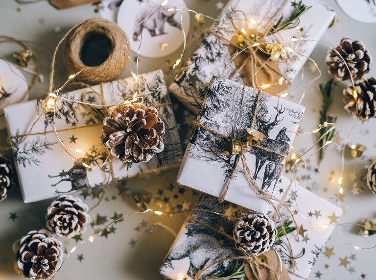 Festliche Tischdekoration zu Silvester mit Geschenken, Tannenzapfen und Lichterketten