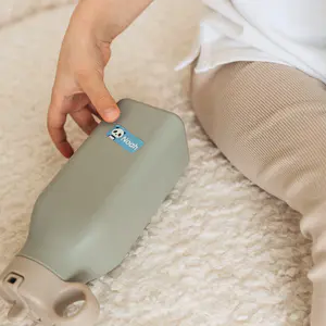 Trinkflasche mit blauem Panda-Namensaufkleber auf einem Teppich neben einem sitzenden Kind