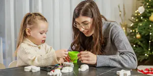 Mutter und Kind basteln gemeinsam Weihnachtsdeko am Tisch