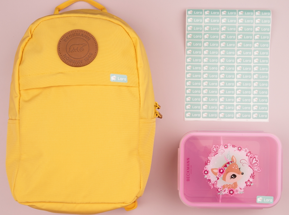 Gelber rucksack, rosa brotdose und ein set mit grünen, personalisierten namensaufklebern