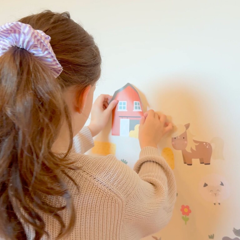 Mädchen klebt Bauernhof Wandsticker an die Wand