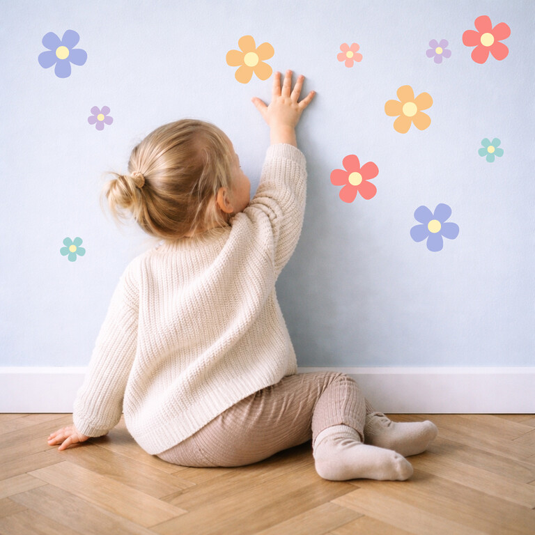 Kind klebt bunte Daisy Wandsticker an die Wand