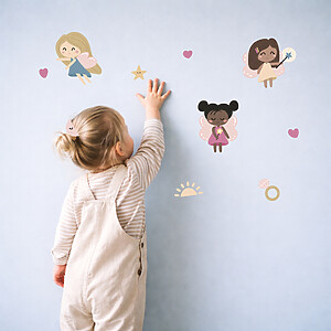 Mädchen klebt Feen Wandsticker an die Wand