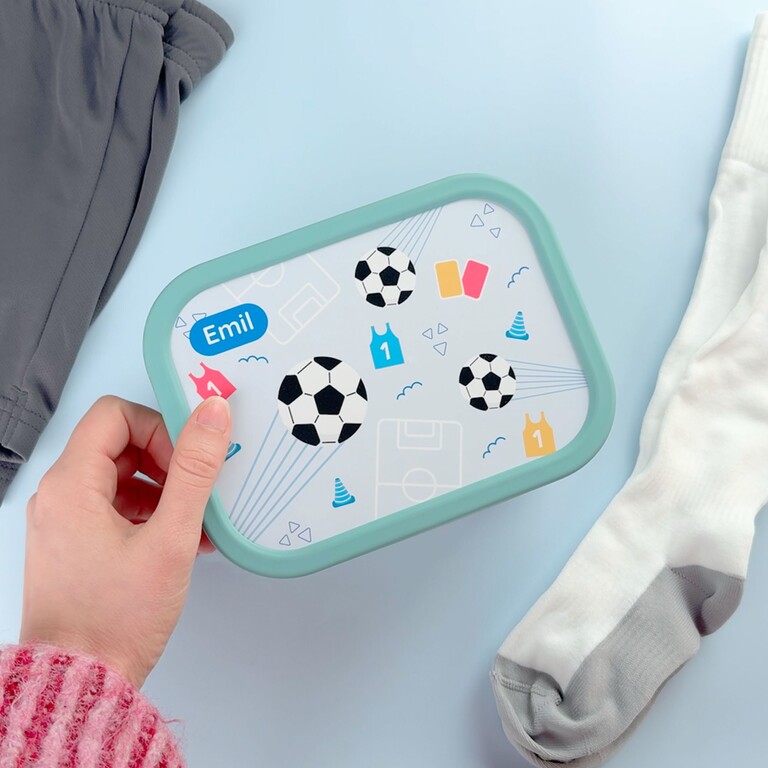 Grüne Fußball-Brotdose in der Hand